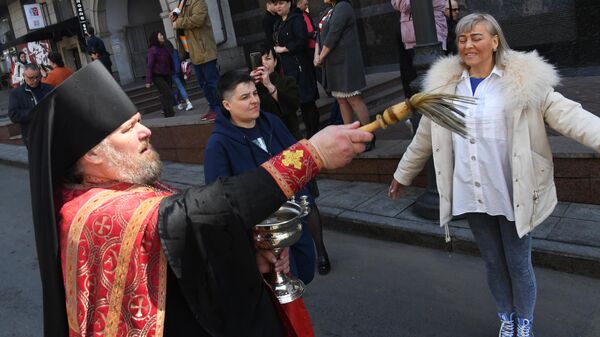 Священник освящает людей во время пасхального крестного хода во Владивостоке