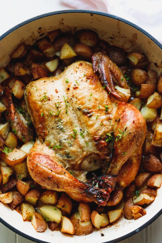 Whole roasted chicken with potatoes in a dutch oven