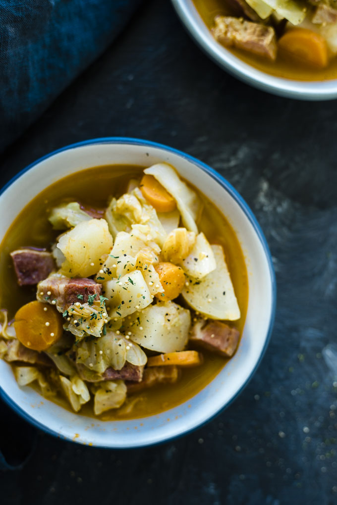 bowl of soup with carrots, potatoes and corned beef garnished with parsley